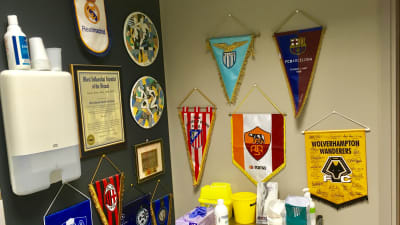 Vimplar av olika fotbollslag hänger på väggen.