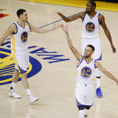 Klay Thompson (t.v.), Stephen Curry (nere) och Kevin Durant tar varandra i händerna.