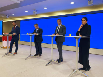 Nasima Razmyar, Jukka Mäkelä, Juhana Vartiainen och Mikko Mäkelä vid ståbord under en presskonferens.