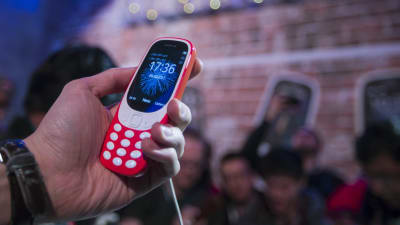 Hand som håller i röd mobiltelefon