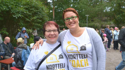 Två kvinnor står bredvid varandra och ler. Båda har på sig vita skjortor med texten korttelicoach.