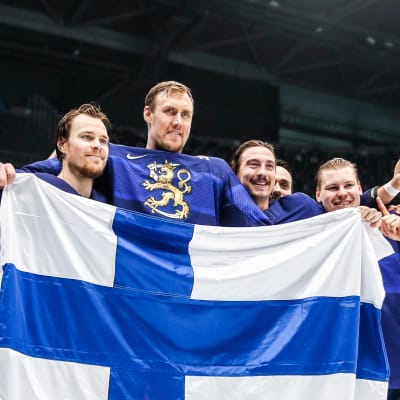 Leijonien pelaajat poseeraavat Suomen lipun kanssa olympiafinaalin jälkeen Pekingissä.