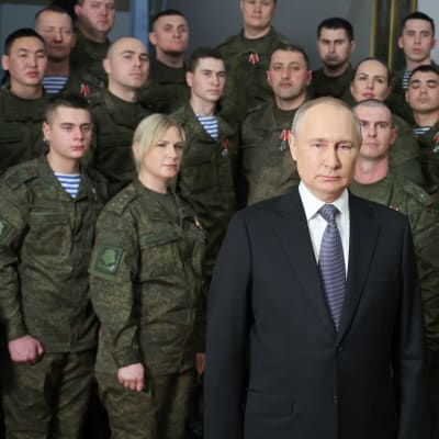 Vladimir Putin seisoo sotilasjoukon edessä.