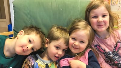 Fyra glada dagisbarn i en grön länstil.