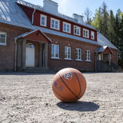 En baskeboll ligger på sandplanen framför Södra Paipis skola och förskola.