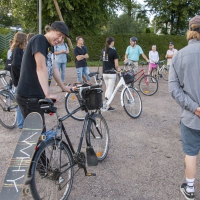 Jaakko Aalto står i en grupp med människor, bak på hans cykel finns hans skejtboard.