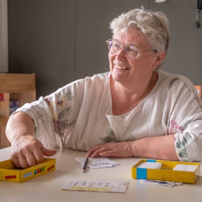 Anne sitter vid ett ord och spelar. Hon är glad.