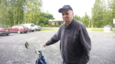 Boris Sjögård står på en grusplan och håller i sin cykel.