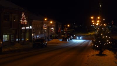 Julbelysning på en gata i Kristinestad. Ljusen till vänster i bilden och som är upphängda i stolpar föreställer julgranar, stjärnor och juleklockor. 