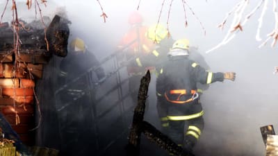Flera brandmän går igenom rök och något som ser ut som ruinerna av en ladugård.