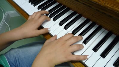 Tangenterna på ett piano, två händer spelar på tangenterna.