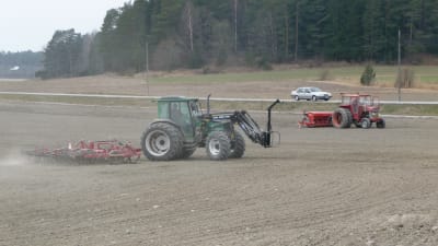 Traktorer på med harv och såmaskin på åkern