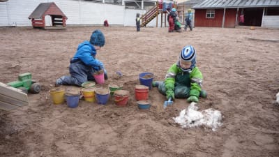 Plasthinkar fyllda med sand, barnhänder som fyller på mera sand.