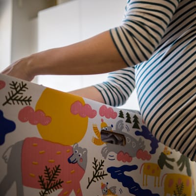 En mamma med gravidmage inspekterar innehållet i en en babylåda.