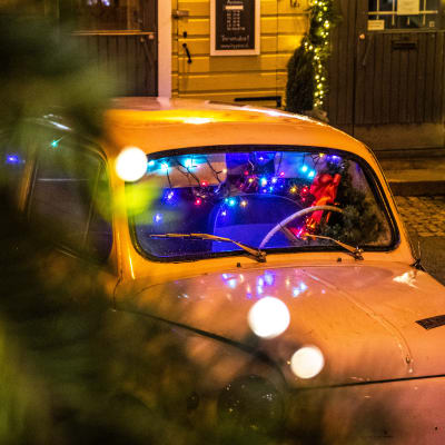 Festlig julbelysning och en gammaldags bil på gatan