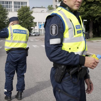 Två polisen står på vägen, redo att utföra blåstest på bilförare. Deras ansikter syns inte.