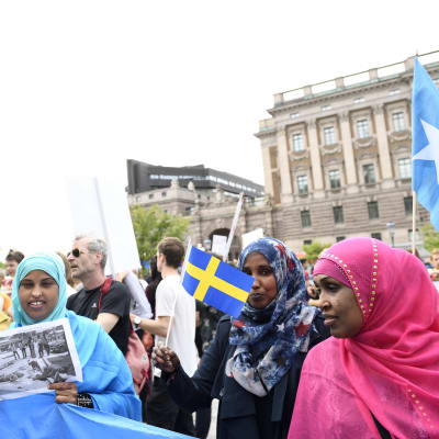 Demonstration utanför Sveriges riksdag. I förgrunden muslimska kvinnor i färgranna slöjor och med Sveriges flagga i handen.