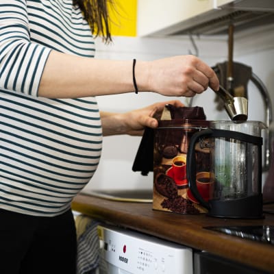 En gravidperson kokar kaffe.