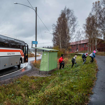 Barn stiger av buss på busshållplats