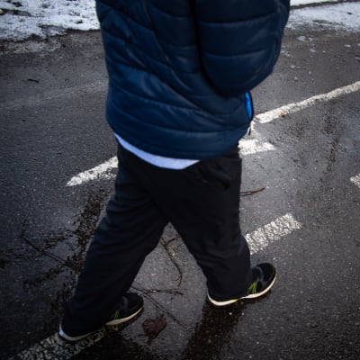Lapsi kävelee tiellä nuoli merkin päältä.