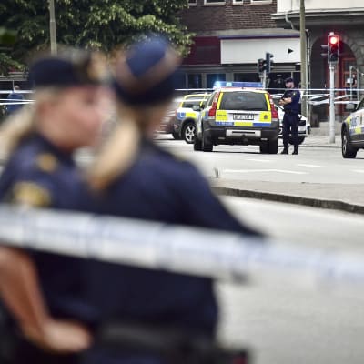Svenska polisbilar och poliser vid en brottsplats.