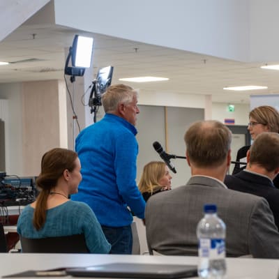 Bengt Gustavsson ställer en fråga på informationstillfället i Lovisavikens skola. På bilden syns Bengt som stpr upp bland publiken och en person som håller en mick framför honom. 