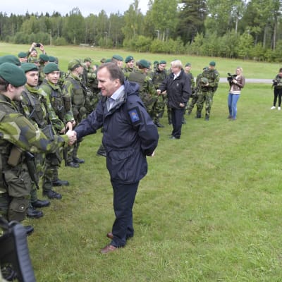 Statsminister Stefan Löfven, med försvarsminister Peter Hultqvist i bakgrunden hälsade på soldater under militärövningen Aurora  i september 2017.