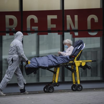 Suojapuvulla varustettu hoitohenkilökunnan edustaja kuljetti paareilla potilasta pariisilaissairaalassa keskiviikkona.