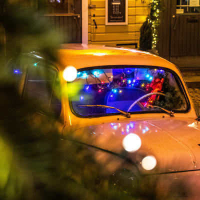 Festlig julbelysning och en gammaldags bil på gatan