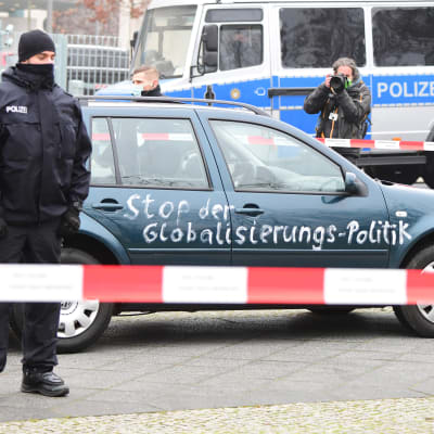 En polis står framför en bil som målats med texten "Stoppa globaliseringspolitiken".