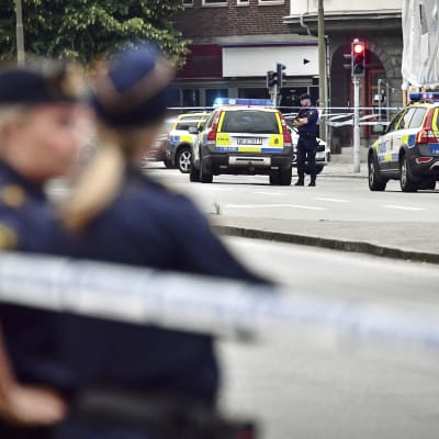 Svenska polisbilar och poliser vid en brottsplats.