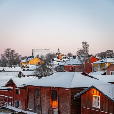 Röda träbodar vid en istäckt åstrand
