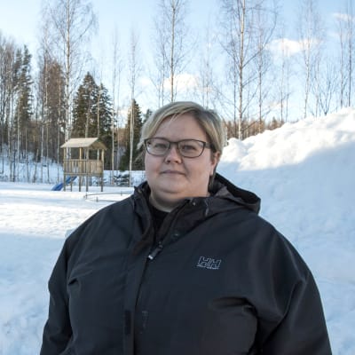 Jannica Ruusunen står på sin gård, i bakgrunden syns en gunga och klätterställning.