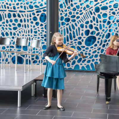 Lilja Haatainen spelar violin intill ett piano.