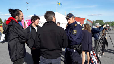 En polisman står och diskuterar med aktiva invånare i Järva. 