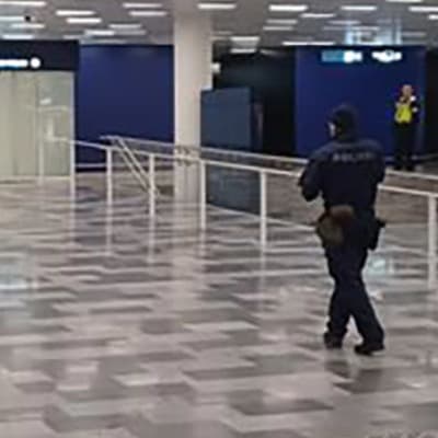 Poliisi lähestyy miestä lentokentällä.