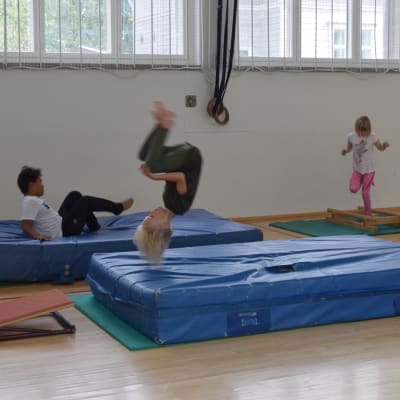 Barn som hoppar i gymnastiksal.