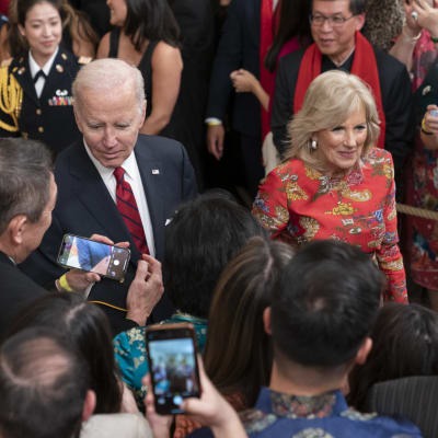 President Joe Biden och hans hustru Jill Biden omgiven av nyfikna människor med mobiltelefoner.