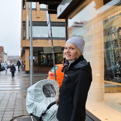 kvinna med bebis står vid hörnet av Lundagatan och Biskopsgatan i Borgå en grå dag i november