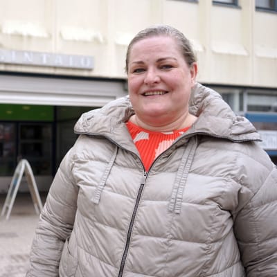 Vaalea nainen katsoo kameraan, päällään harmaa toppatakki.