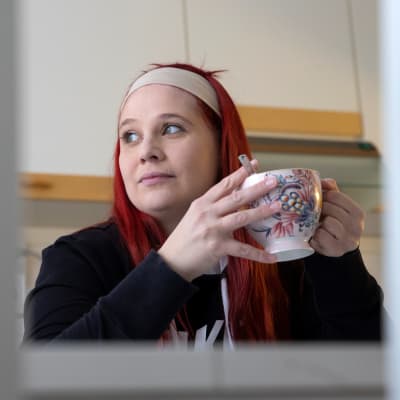 Laura juo teetä ja katsoo kaukaisuuteen.