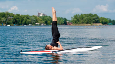 Kvinna på surfbräde som yogar i vattnet.