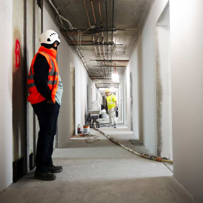 Byggarbetare står i en korridor. 