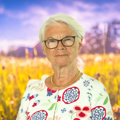 Elisabeth Tarras-Wahlberg ser rakt in i kameran, i bakgrunden syns en sommaräng.