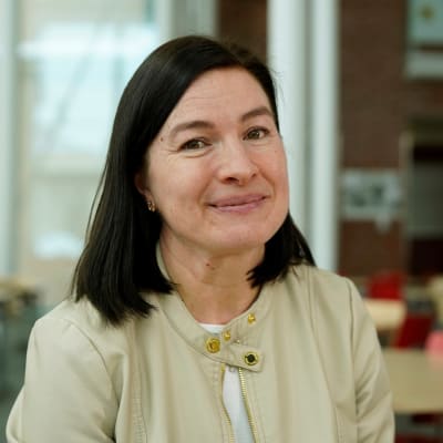 kvinna med brunt hår ler mot kameran