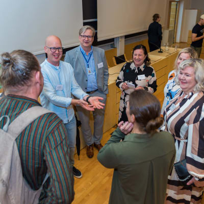 Panelikeskustelijat kerääntyneet rinkiin ennen keskustelua.