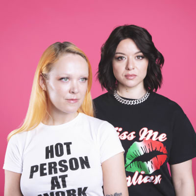 Radiojuontajat ja dj:t Taika Mannila ja Lina Schiffer poseeraavat pinkkiä taustaa vasten.