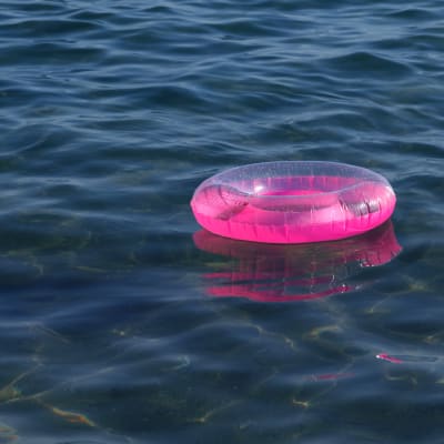 En rosa badring mot mörkt vatten.