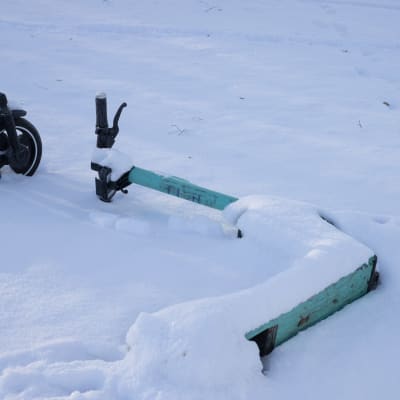 En elsparkcykel ligger omkull i snödriva.
