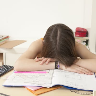 Flicka har somnat över sina skoluppgifter